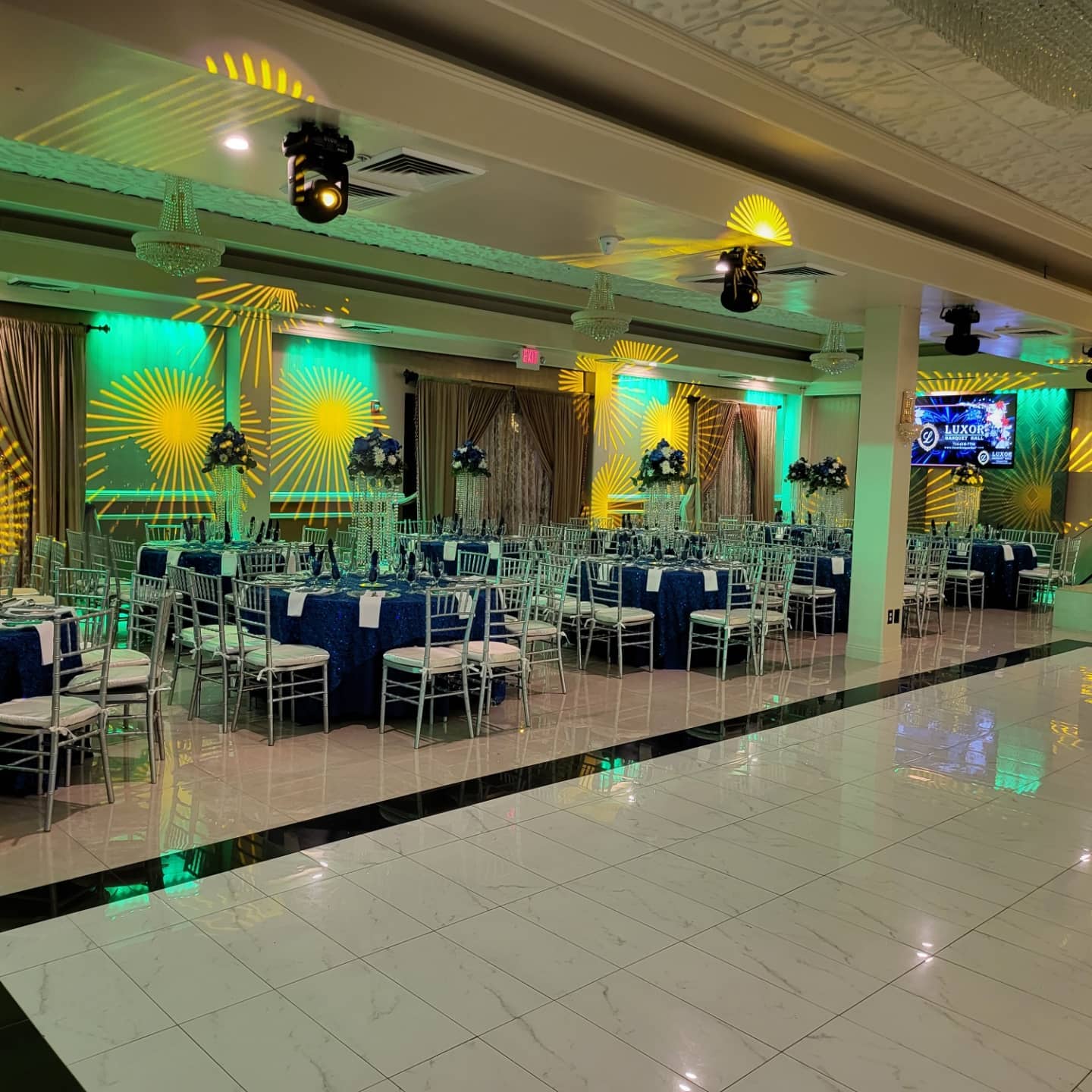 Elegant event setup with blue tablescapes and stage lighting